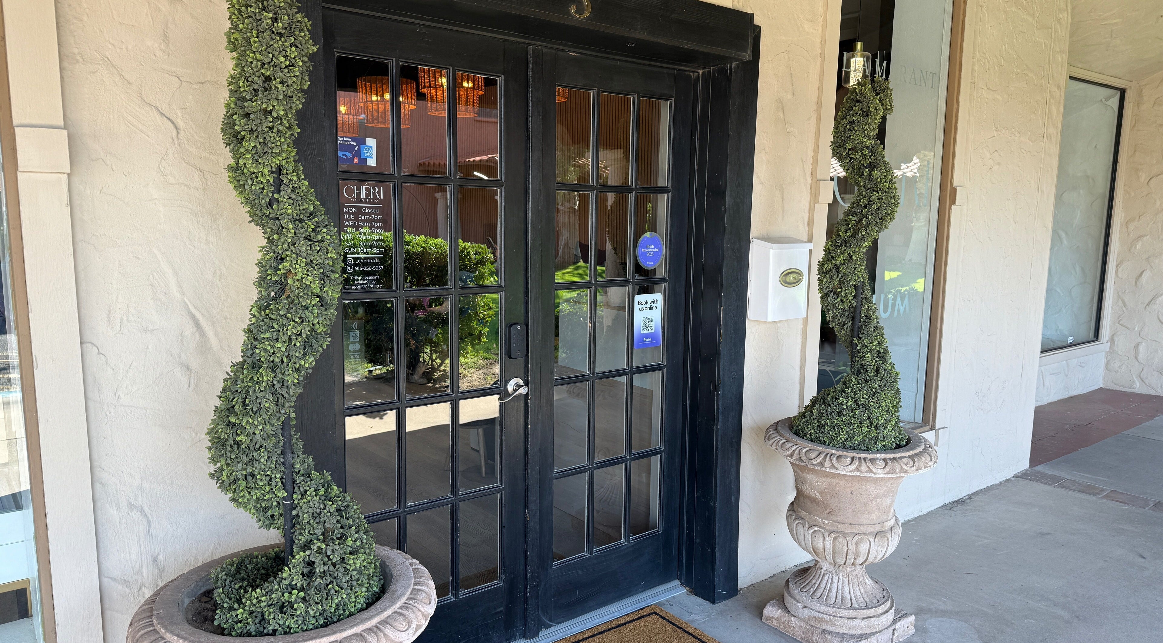 Front entrance of Chéri Nails and Spa, El Paso, Texas, US, adorned with topiary plants.