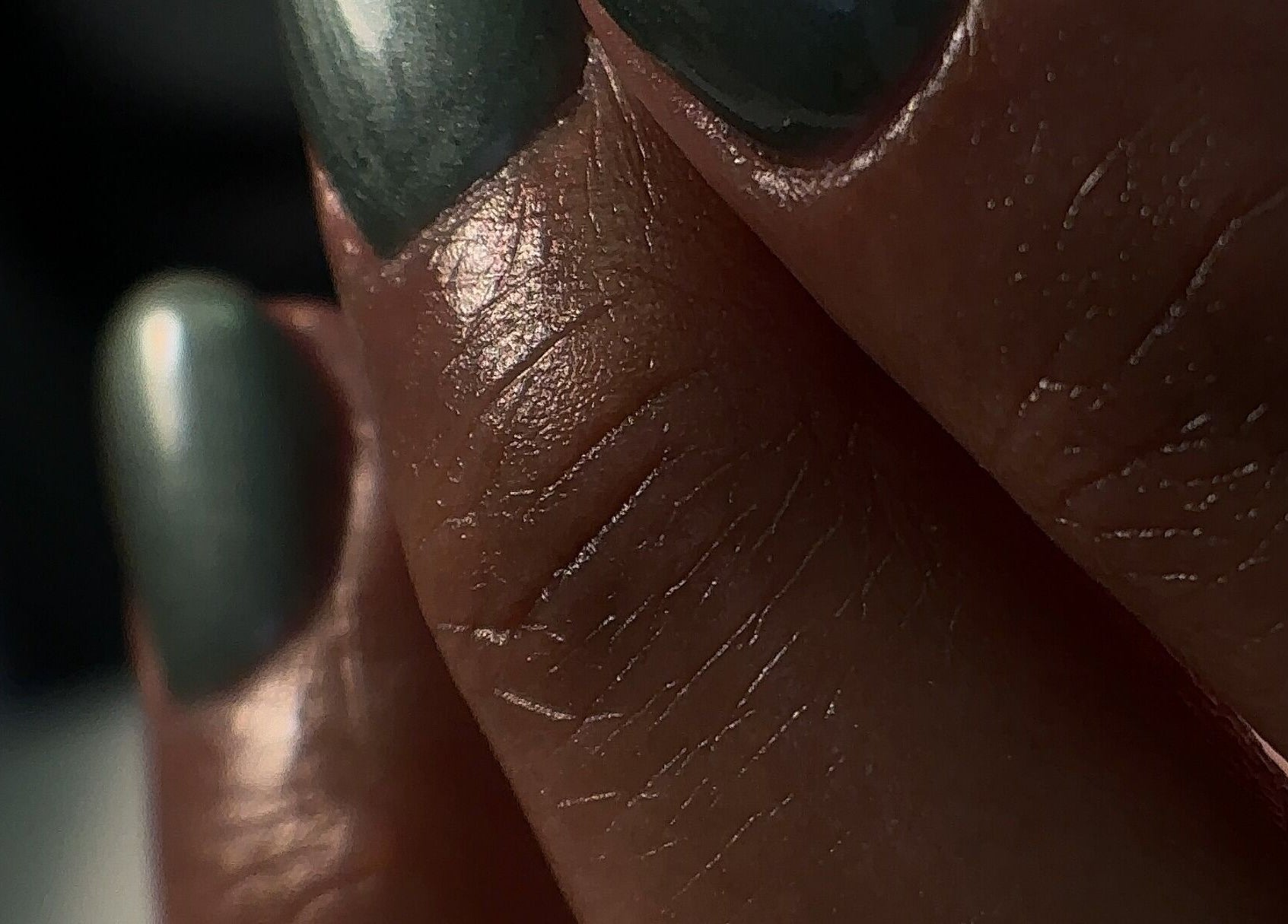 Close-up of elegantly polished nails with a green sheen at Chéri Nails and Spa, El Paso, Texas, US.