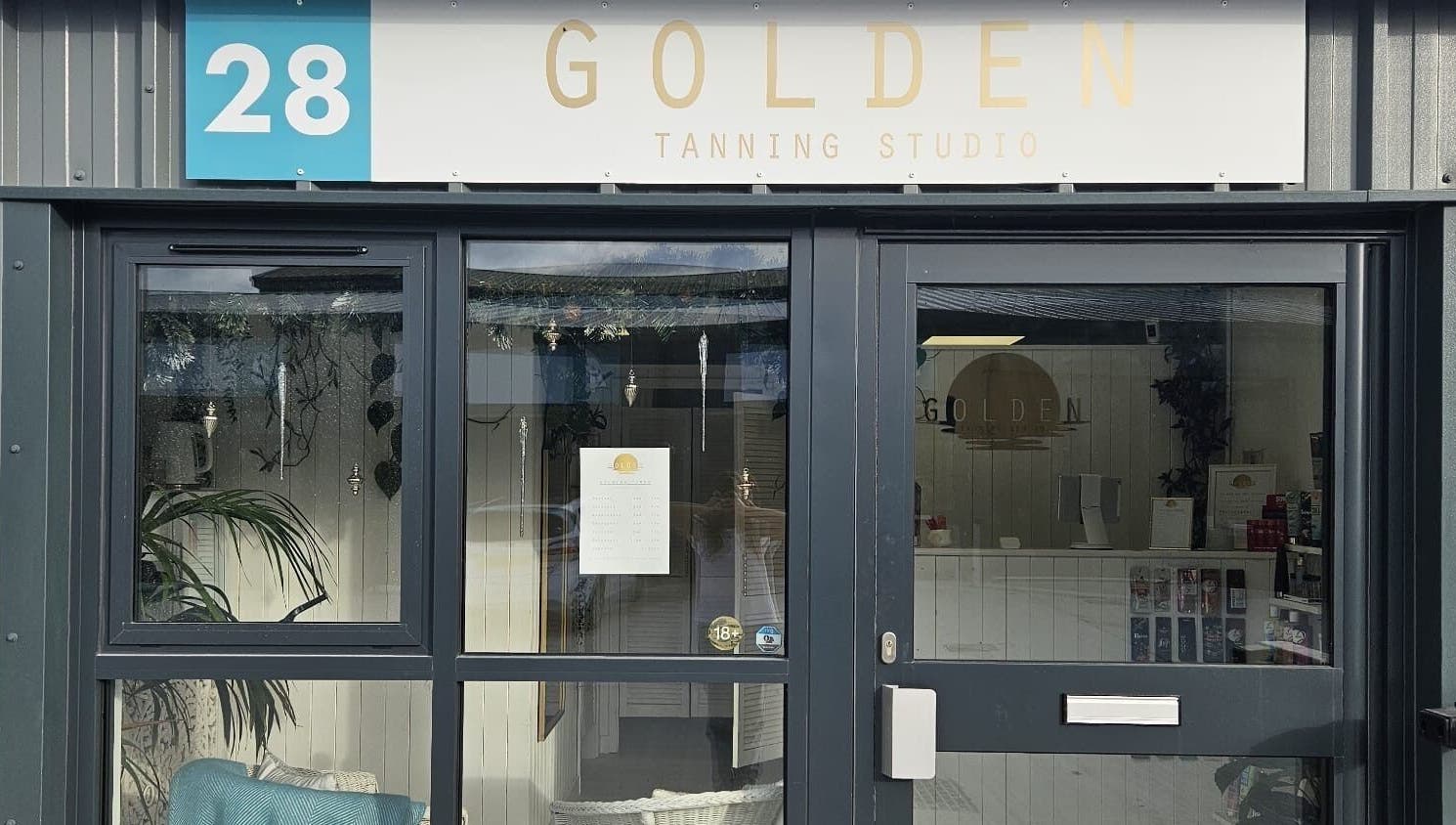 Entrance of Golden Tanning Studio in Wadebridge, England, GB showcasing a modern glass facade and welcoming ambiance.
