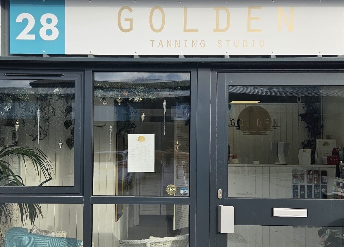 Entrance of Golden Tanning Studio in Wadebridge, England, GB showcasing a modern glass facade and welcoming ambiance.