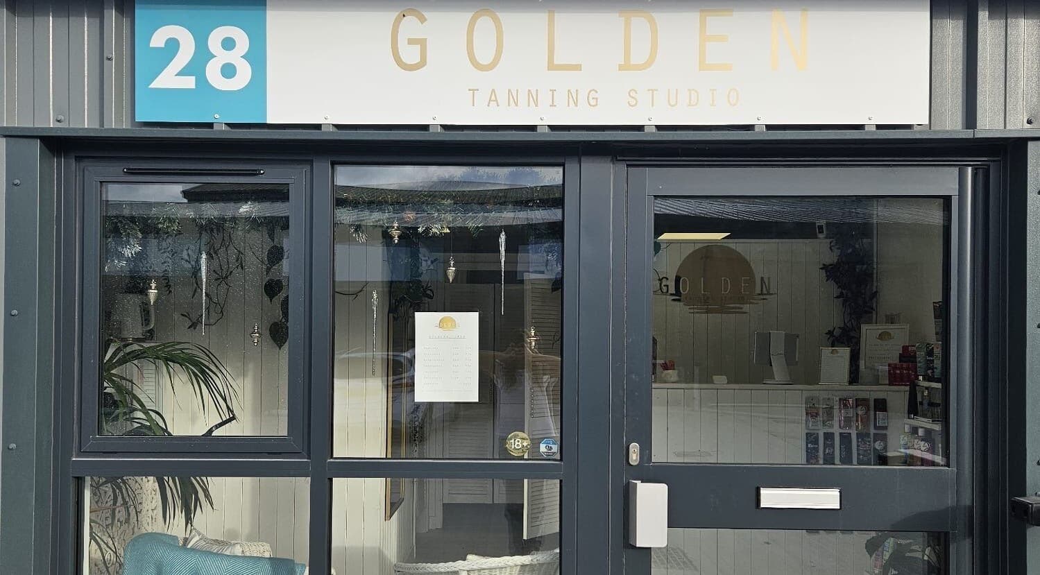 Entrance of Golden Tanning Studio in Wadebridge, England, GB showcasing a modern glass facade and welcoming ambiance.