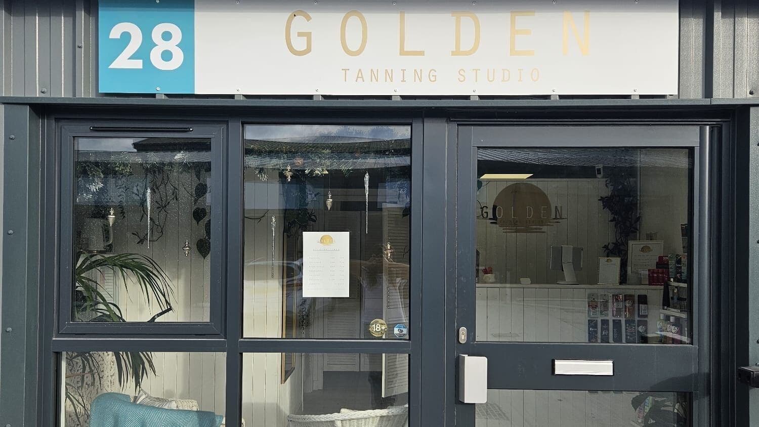 Entrance of Golden Tanning Studio in Wadebridge, England, GB showcasing a modern glass facade and welcoming ambiance.