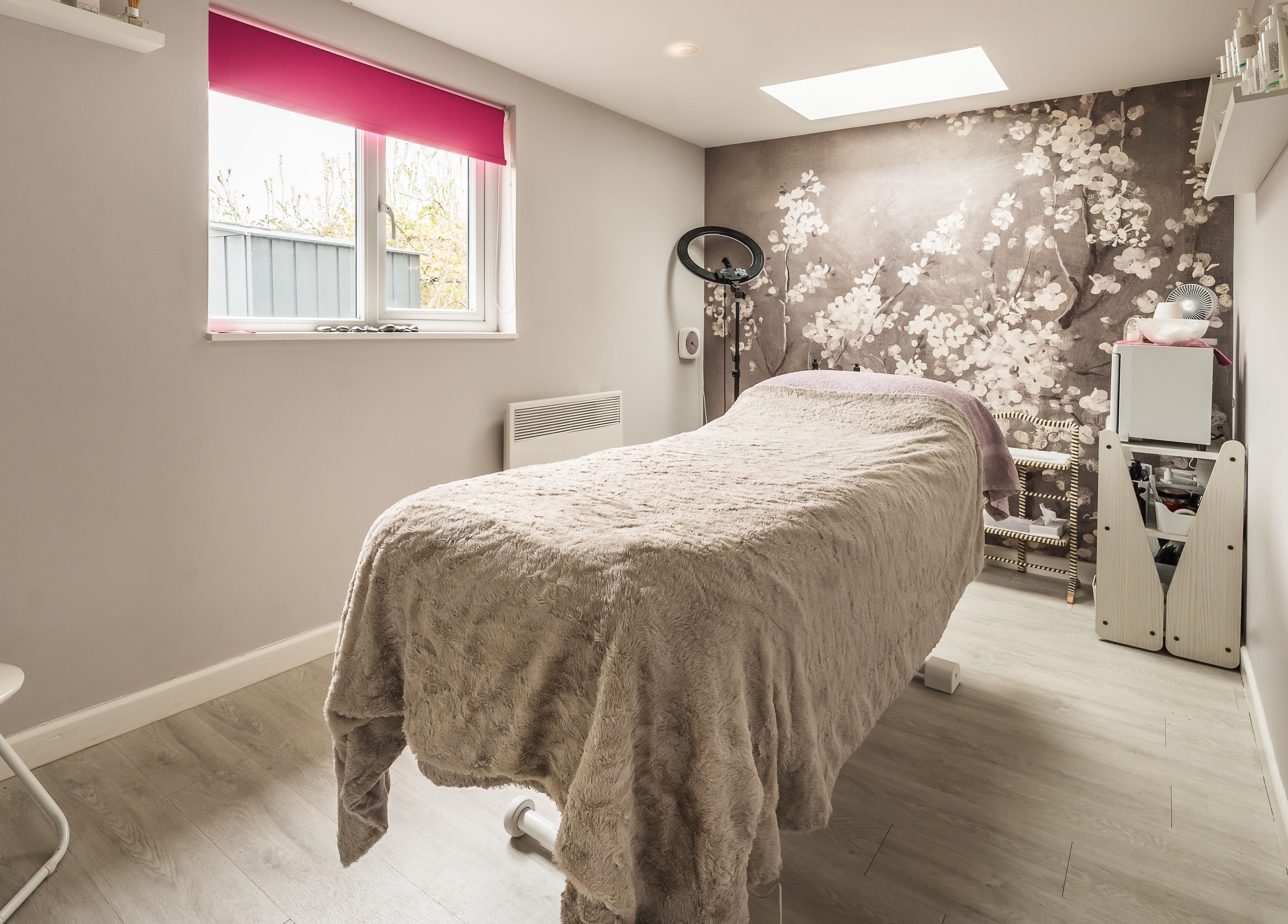 Tranquil treatment room at Fuchsia Beauty, Bristol, England, GB with plush bed and floral decor.