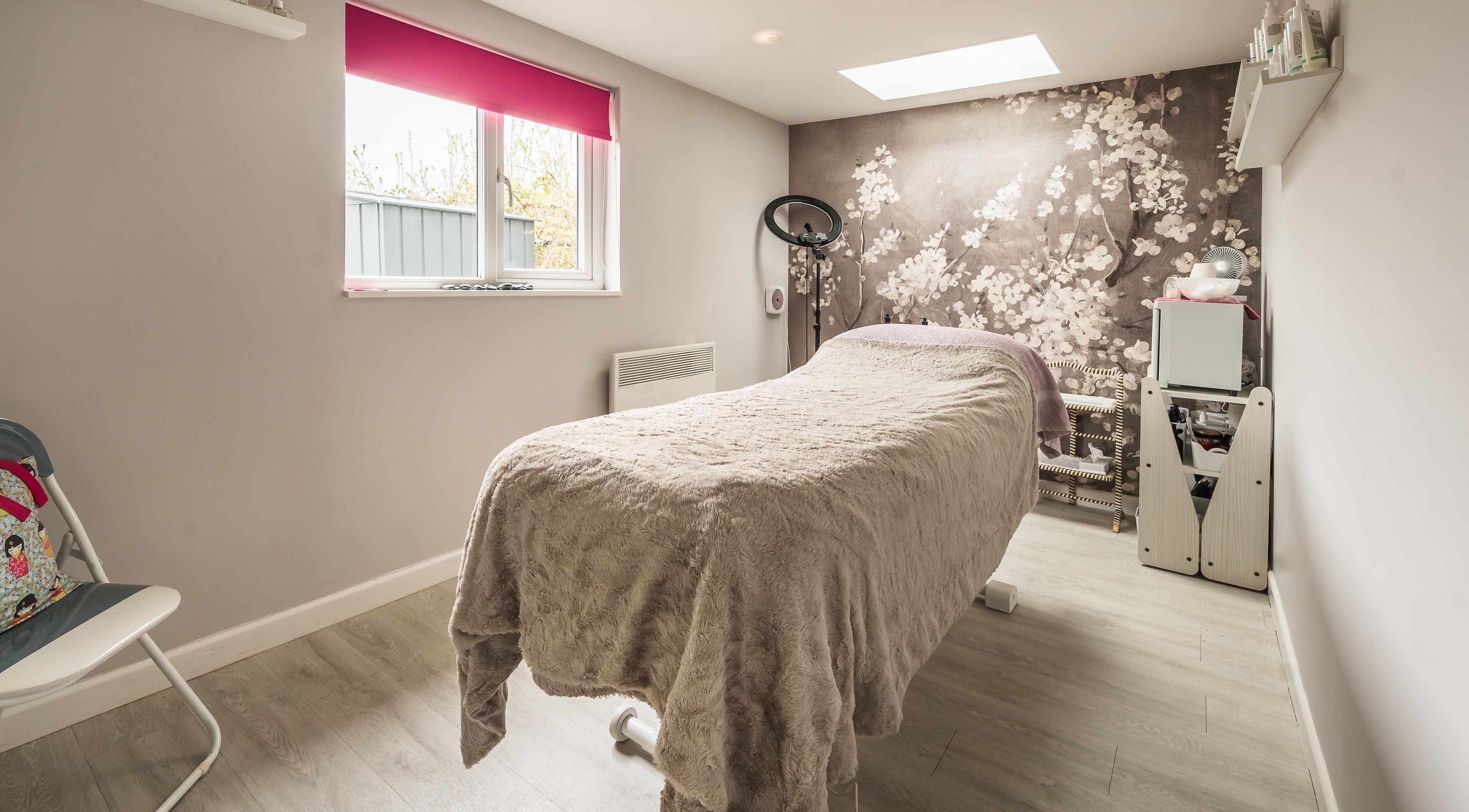 Tranquil treatment room at Fuchsia Beauty, Bristol, England, GB with plush bed and floral decor.