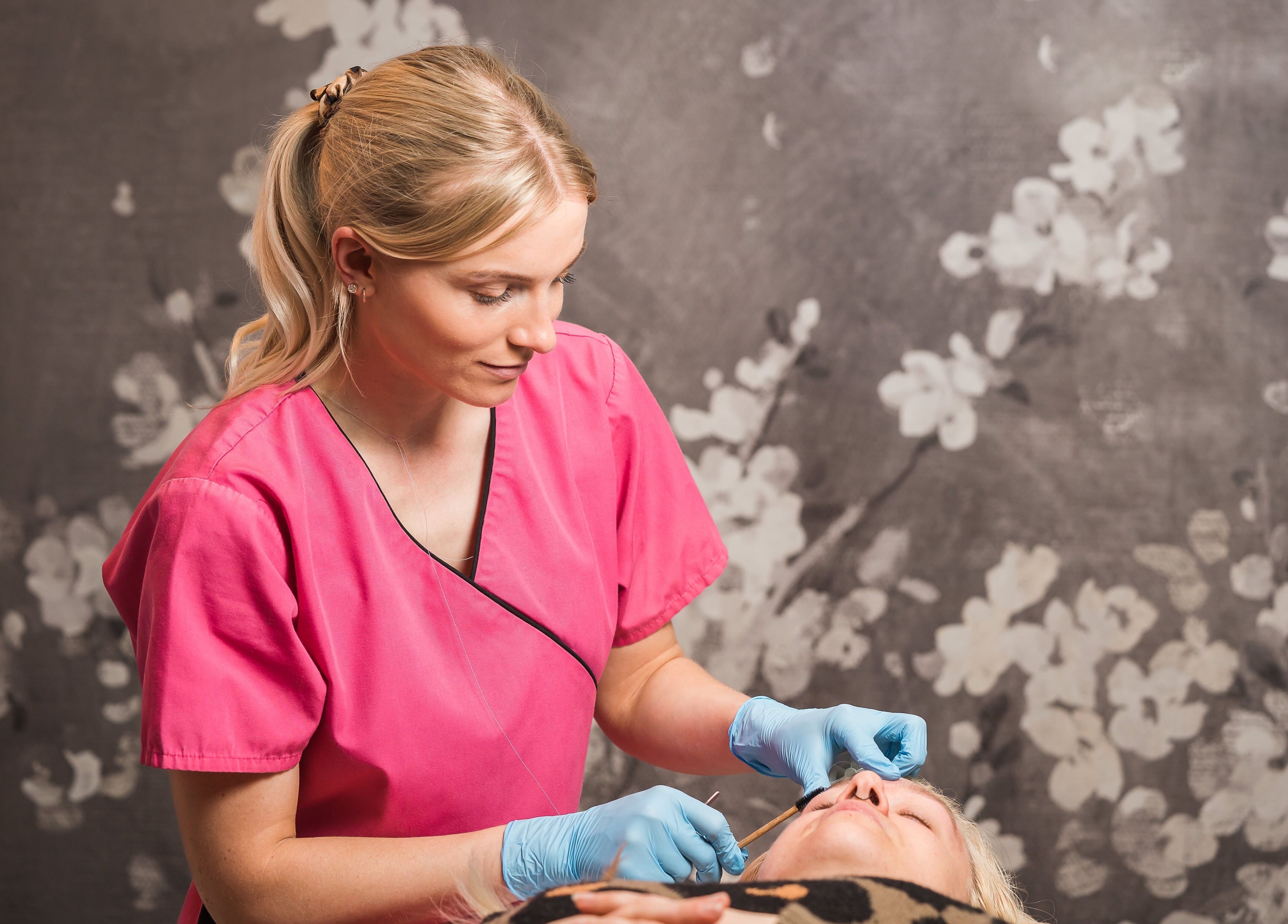 Fuchsia Beauty professional providing facial treatment in Bristol, England, GB with serene floral backdrop.