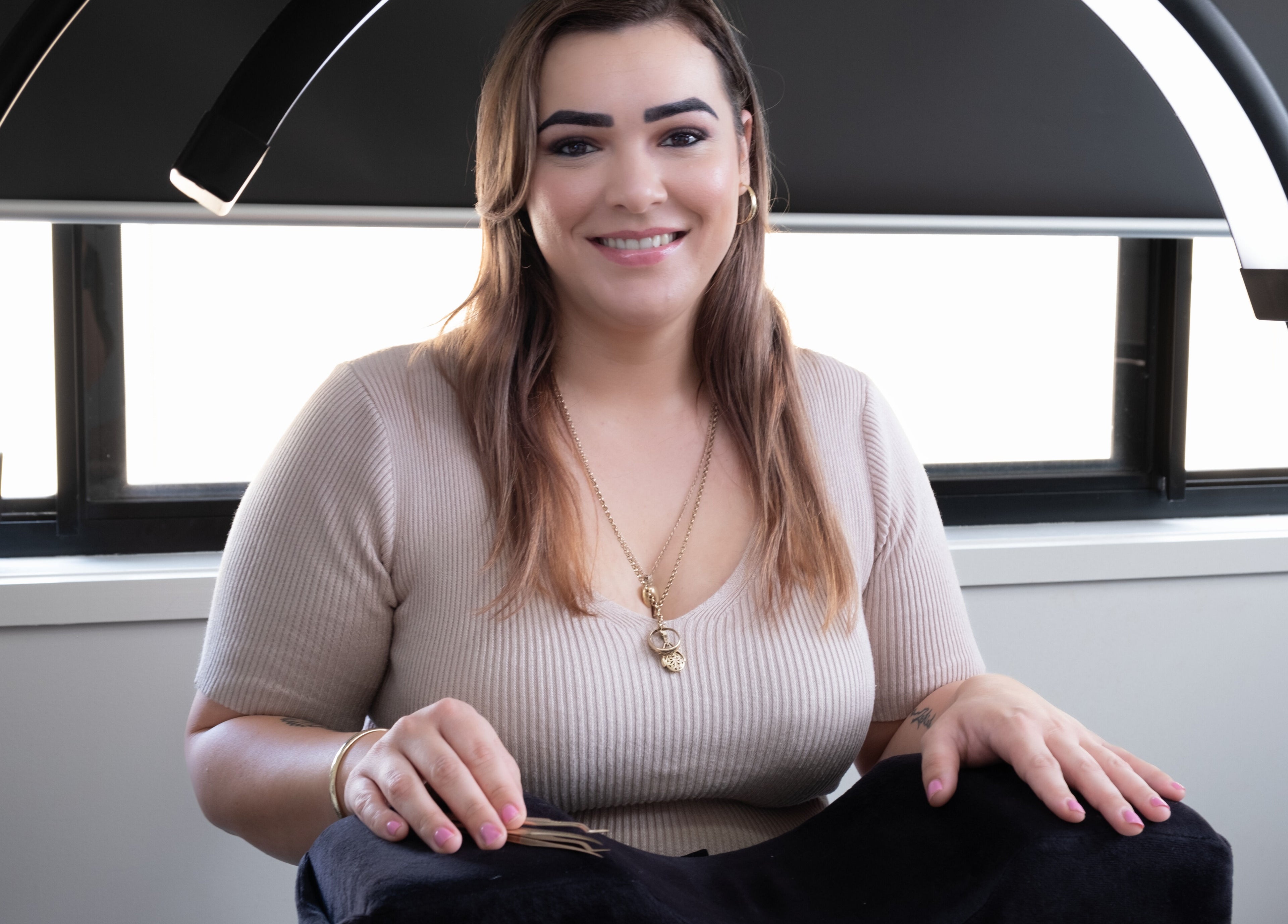 Lash technician at Flutter Your Lashes, Redland Bay, Queensland, AU, smiling beside an eyelash station.