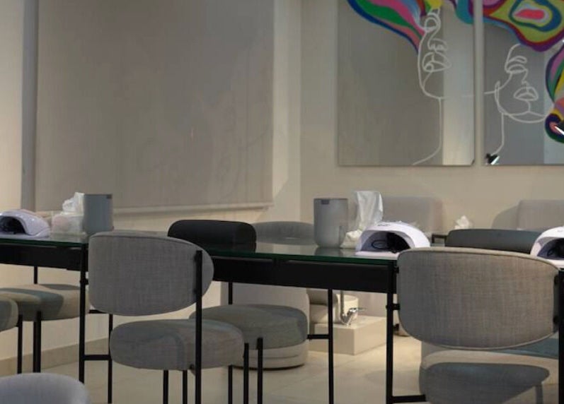 Modern nail station at Gloss'd Beauty Bar, Amman, Amman Governorate, JO, with sleek seating and vibrant wall art.