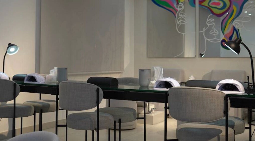 Modern nail station at Gloss'd Beauty Bar, Amman, Amman Governorate, JO, with sleek seating and vibrant wall art.