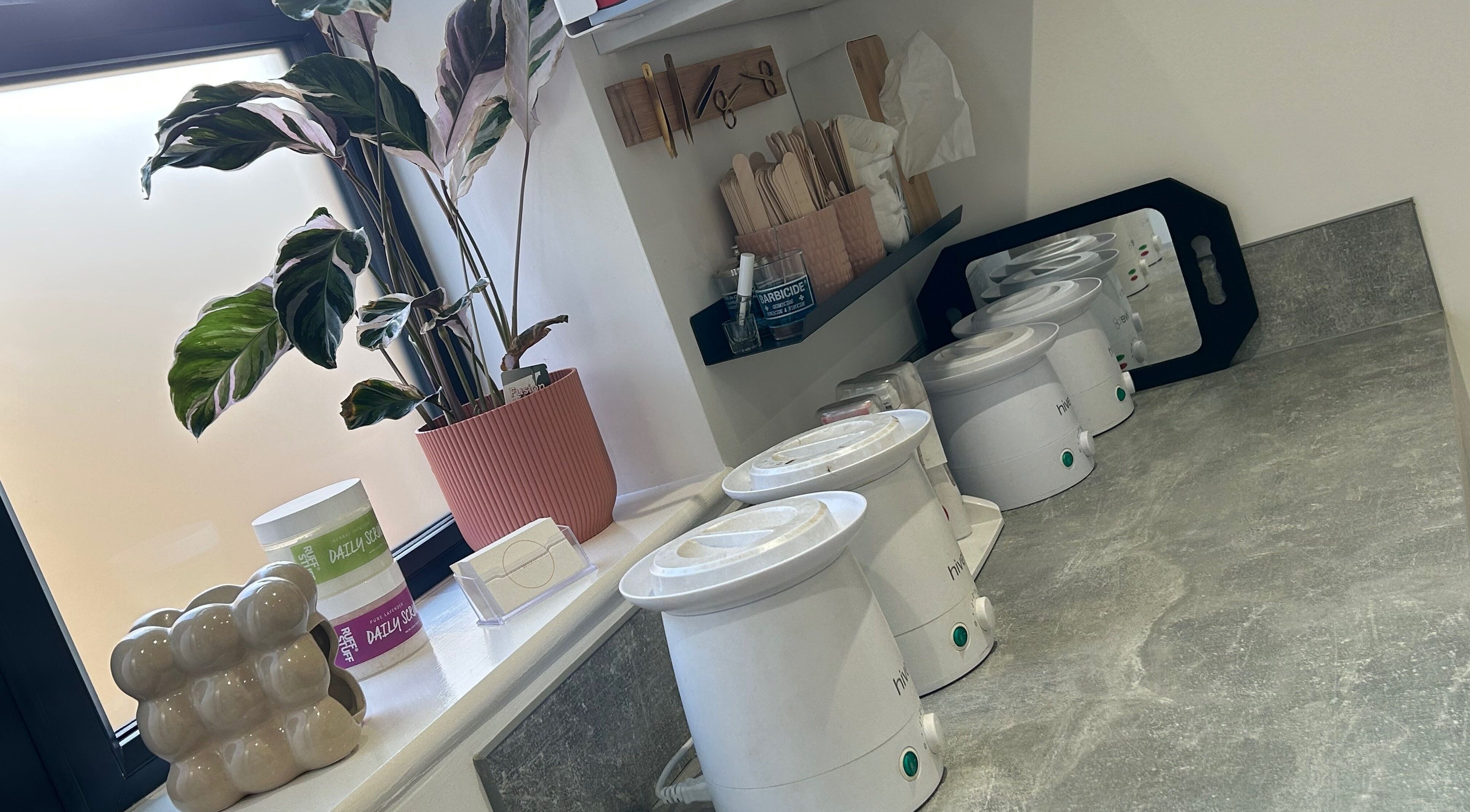 Waxing station setup at The Wax Wife, Exmouth, England, GB featuring warmers, plant, and skincare products.