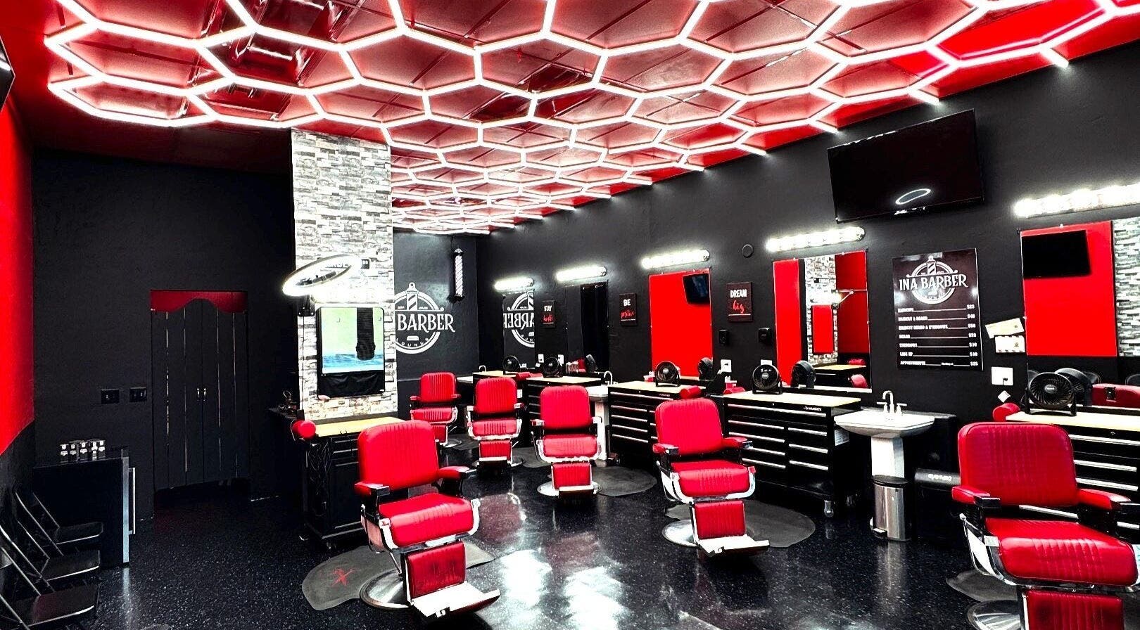 Modern interior of INA Barber Lounge in Tucson, Arizona, US with red chairs and sleek black decor.