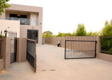 Modern entrance at Bonaire Beauty By X in Kralendijk, Bonaire, BQ with sleek metal gates and lush greenery.