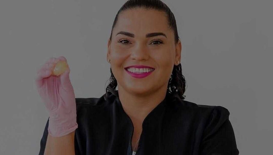 Smiling beauty therapist at Bonaire Beauty By X in Kralendijk, Bonaire, BQ holding a skincare product.