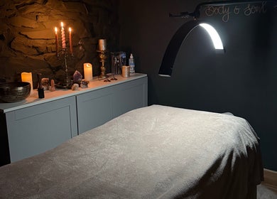 Calming therapy room at Mrs Peony, Shepshed, England, GB, featuring soft candlelight and a comfortable massage table.