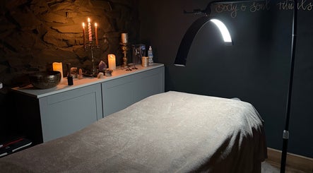Calming therapy room at Mrs Peony, Shepshed, England, GB, featuring soft candlelight and a comfortable massage table.