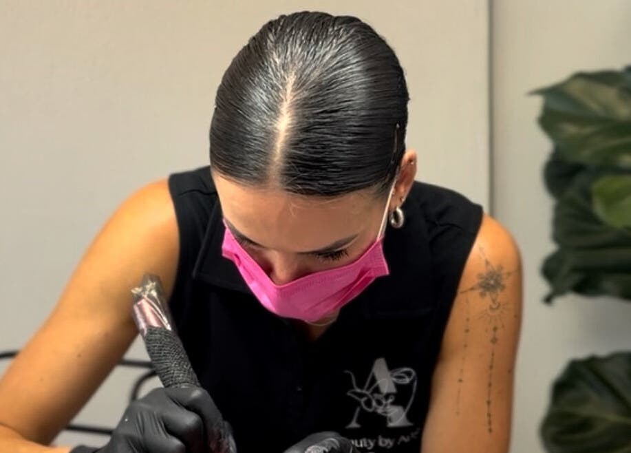 Tattoo artist at Angelic Aesthetics in Cape Town, Western Cape, ZA, focusing intently on a design.