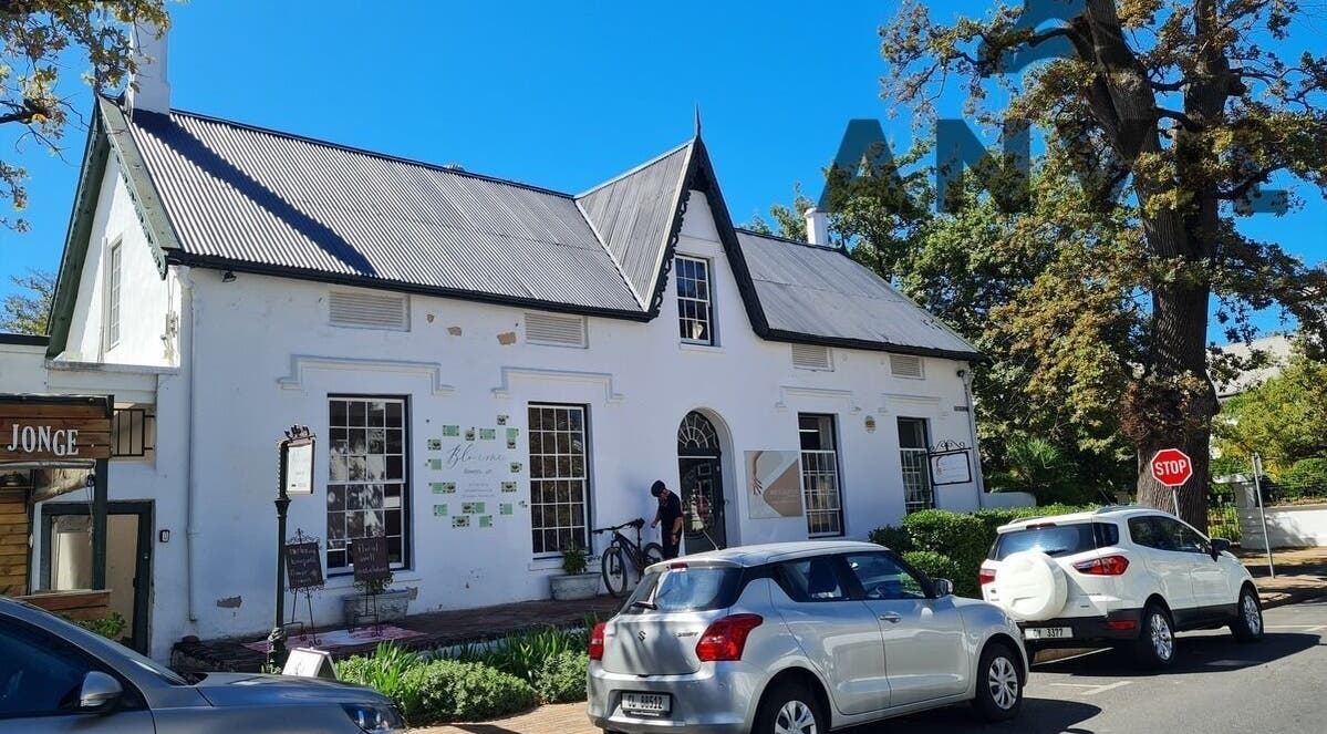 Charming white building of Estelle's Skin Body Nails in Stellenbosch, Western Cape, ZA, surrounded by greenery.