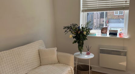 A serene room at Beetox Aesthetics, Broseley, England, GB with a comfy couch, flowers, and window light.