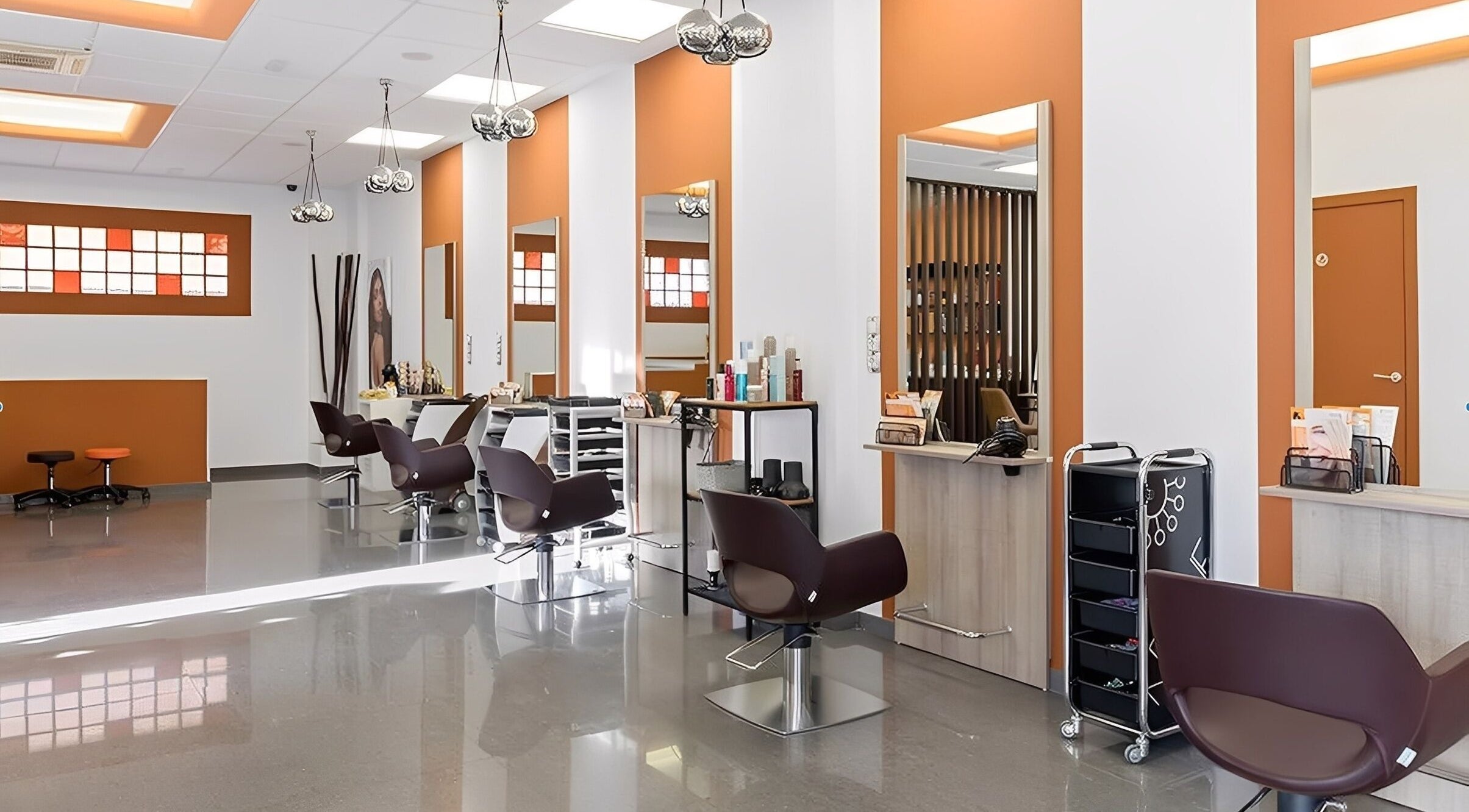 Salón moderno y luminoso en Brown&Naranja Estilistas Meco, Meco, ES, con diseño elegante y sillas de cuero.