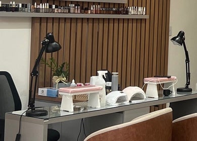 Mesa de manicure no Estúdio Valen, Rio Grande Do Sul, decorada com lâmpadas e produtos de beleza equilibrados.