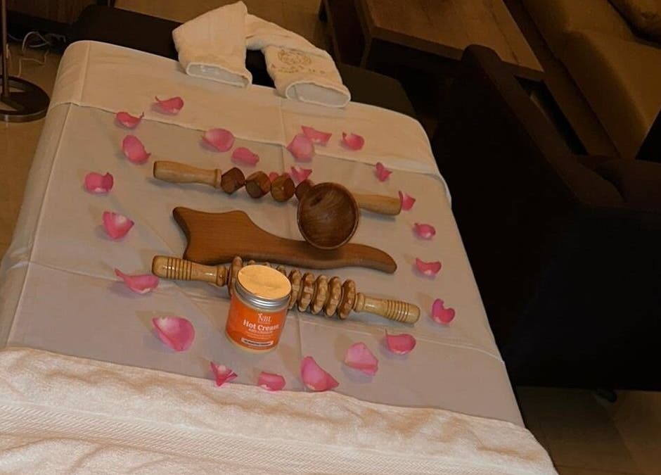 Massage table with wooden tools and petals at Aesthetic Home Spa | Abu Dhabi, Abu Dhabi, AE.
