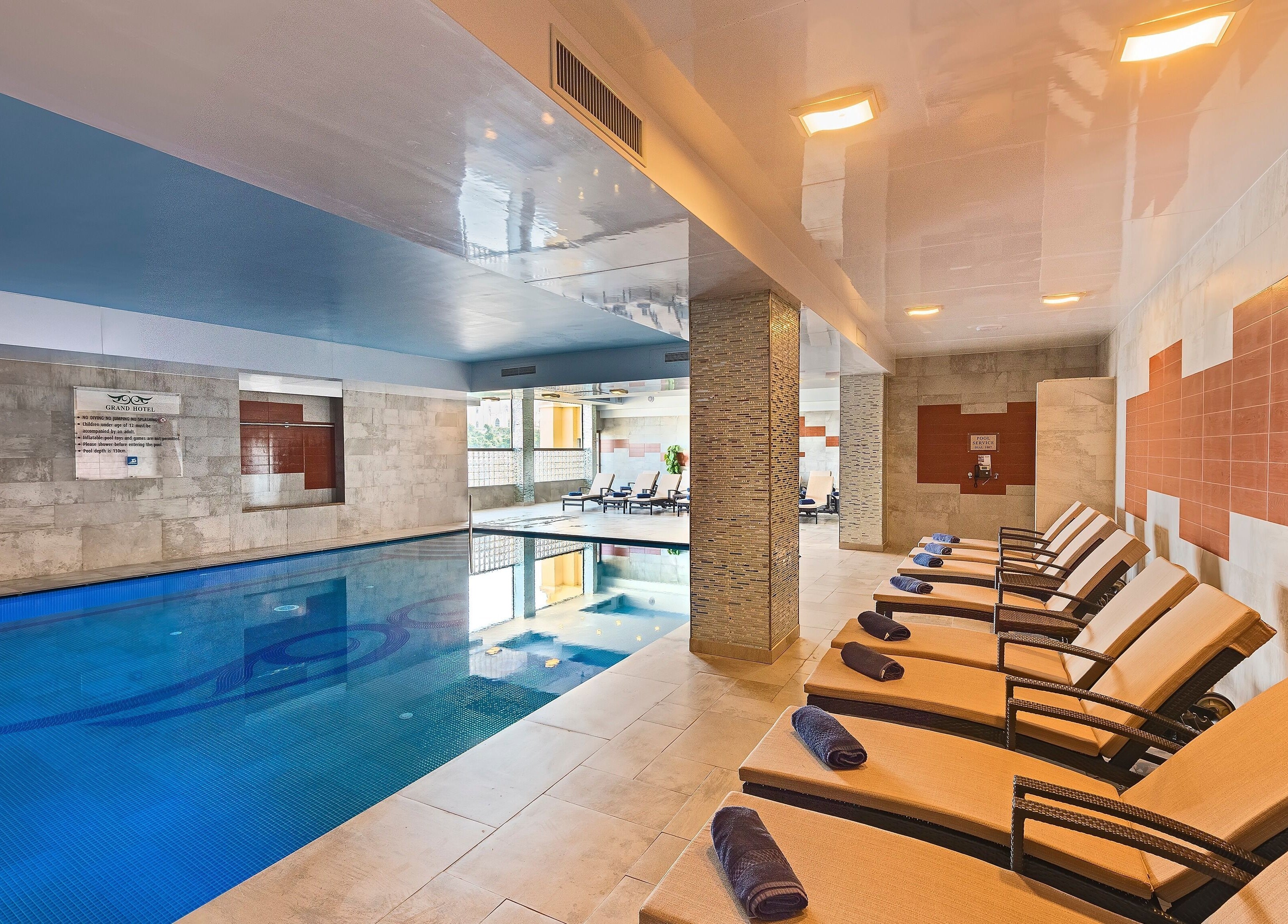 Relaxing indoor pool at The Grand Hotel Elemis Spa, Gozo, MT with sun loungers and elegant design.