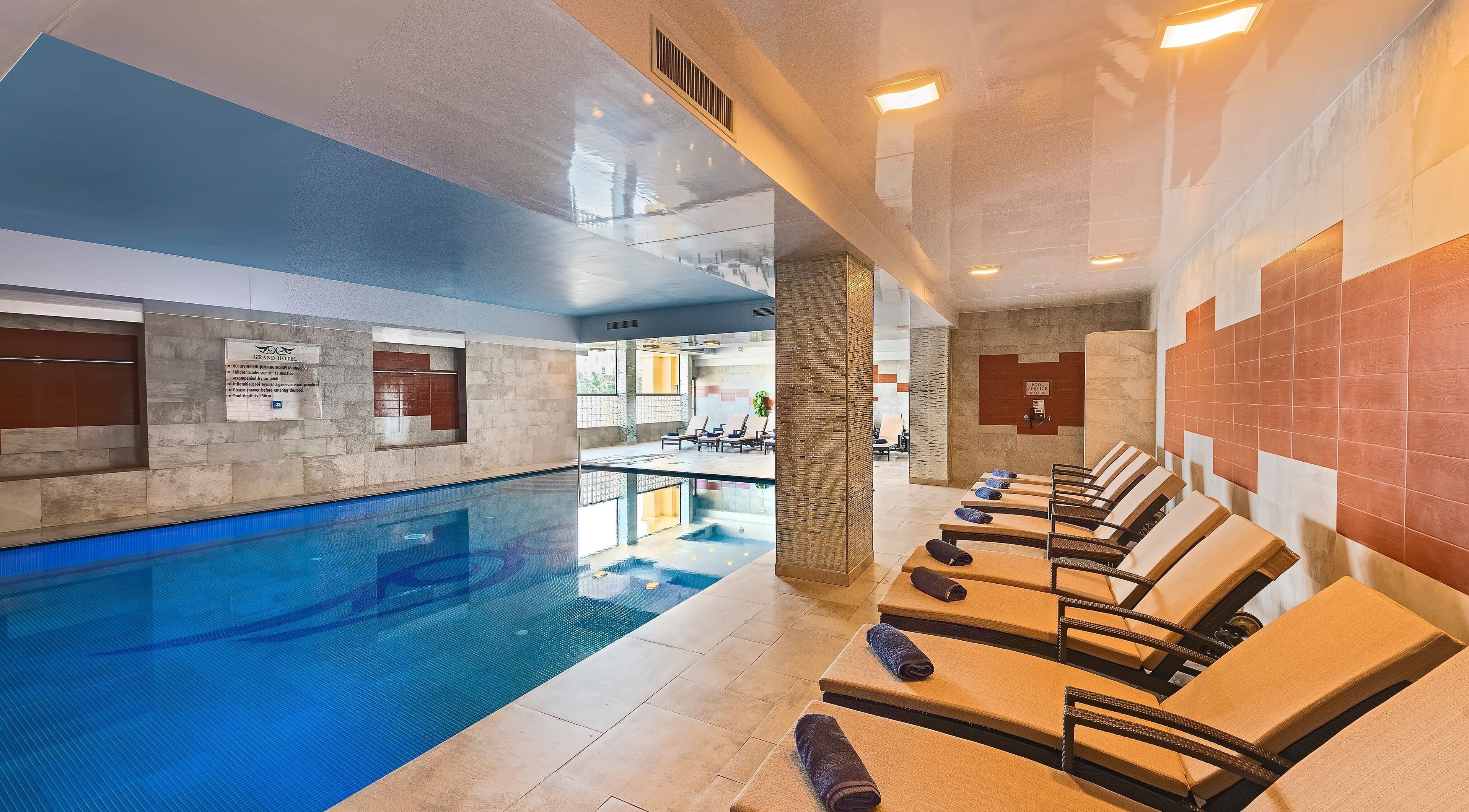 Relaxing indoor pool at The Grand Hotel Elemis Spa, Gozo, MT with sun loungers and elegant design.