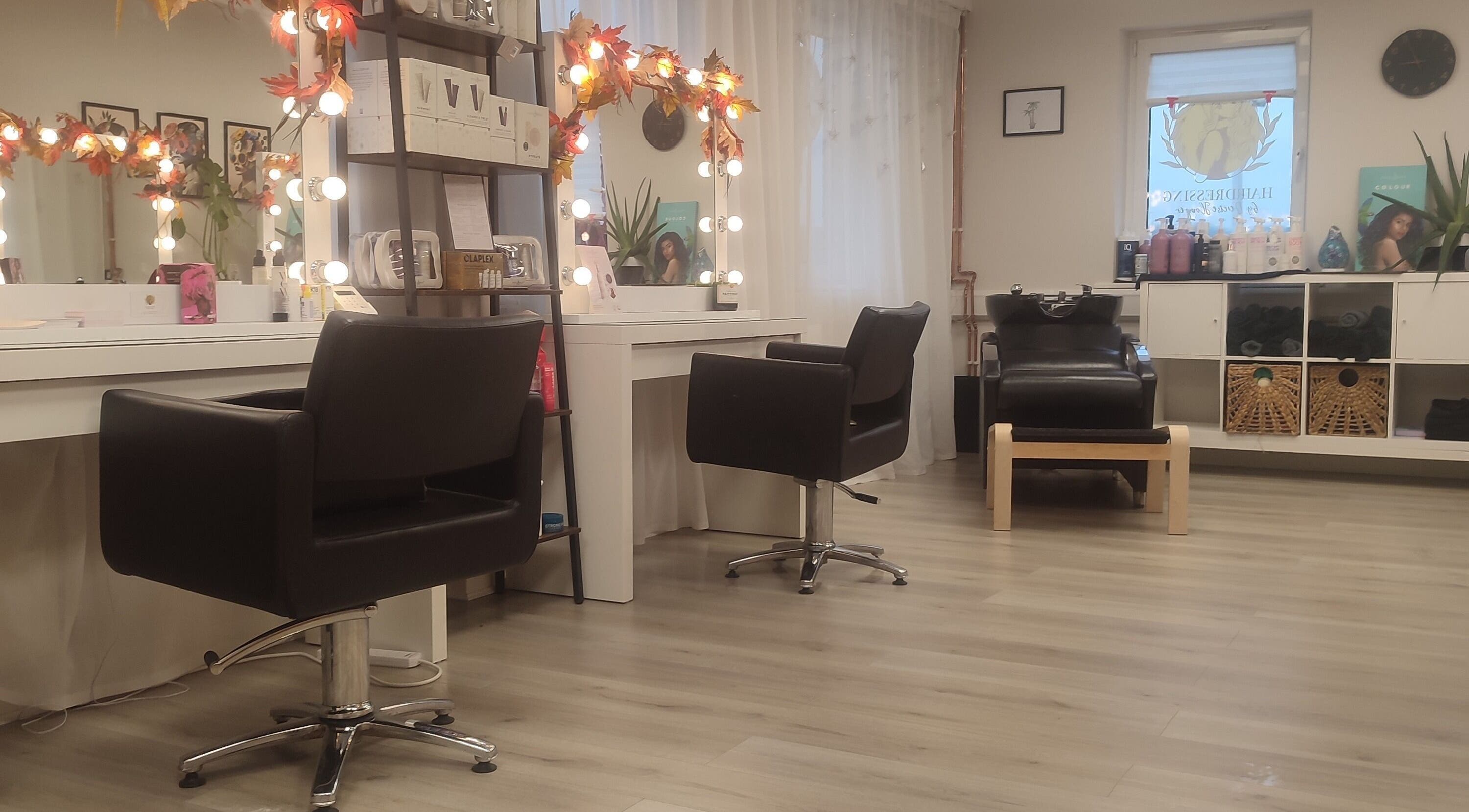 Elegant interior of Jessica Gilbert Hair salon in Corbridge, England with stylish chairs and lit mirrors.