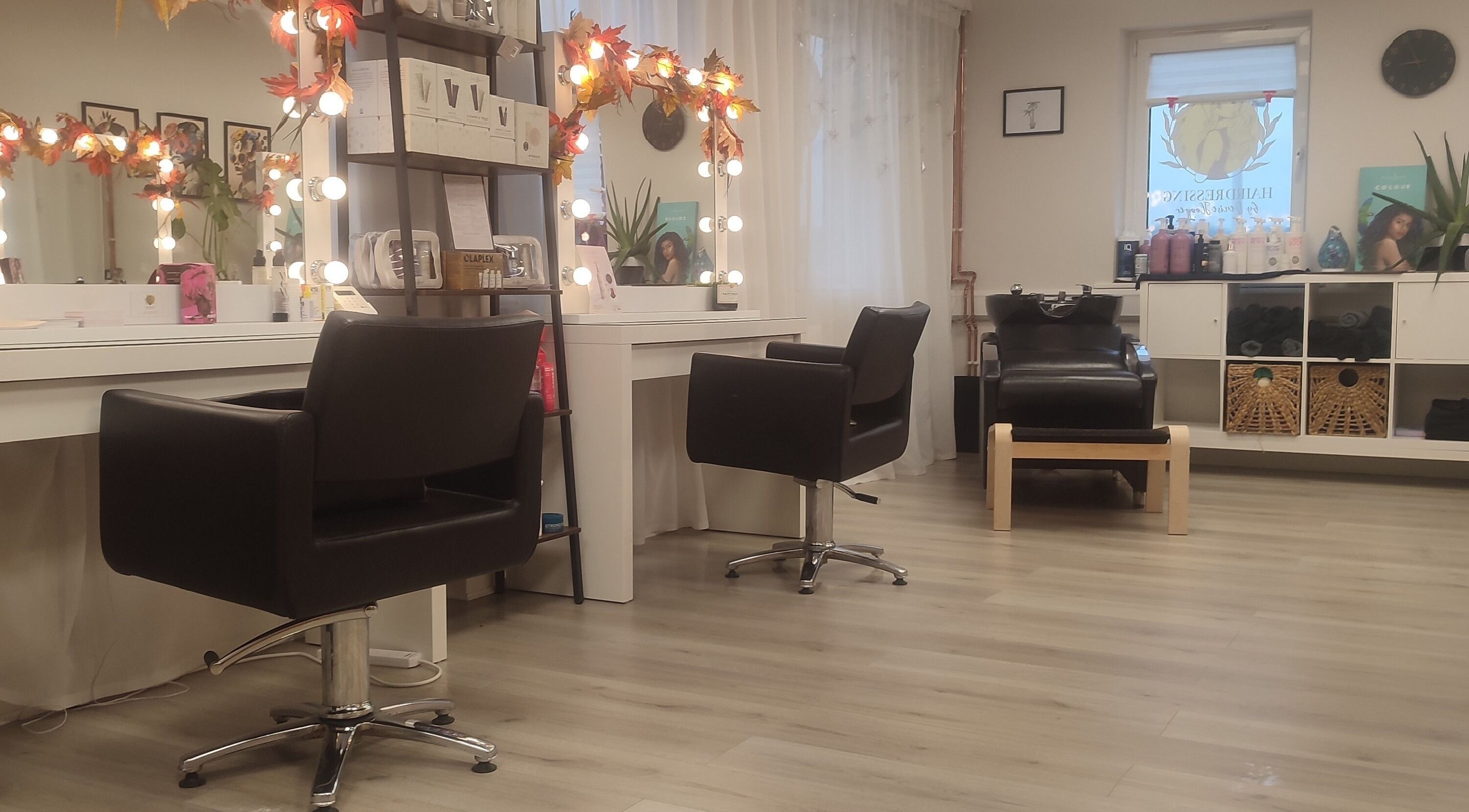 Elegant interior of Jessica Gilbert Hair salon in Corbridge, England with stylish chairs and lit mirrors.