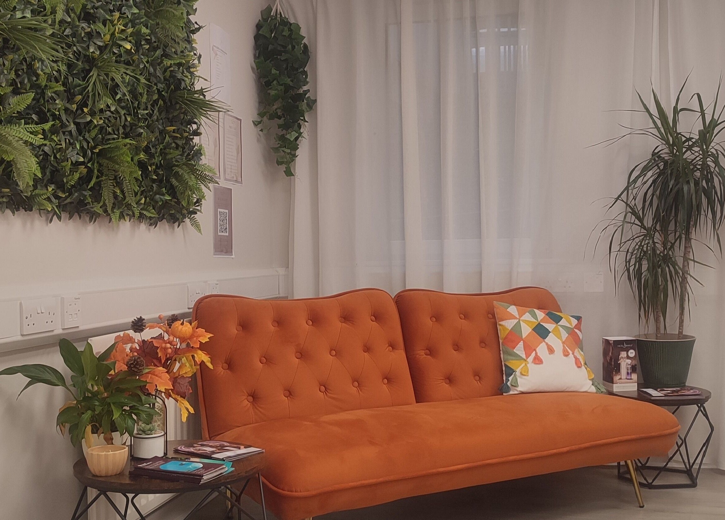 Cozy orange sofa with plants at Jessica Gilbert Hair, Corbridge, England. Inviting and stylish decor.