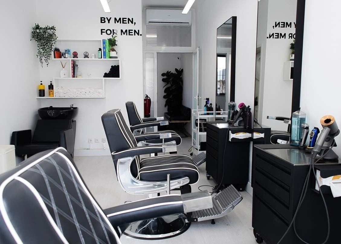 Interior elegante da Boldmen’s Salon em Estoril, Lisboa, PT, com cadeiras e espelhos modernos.