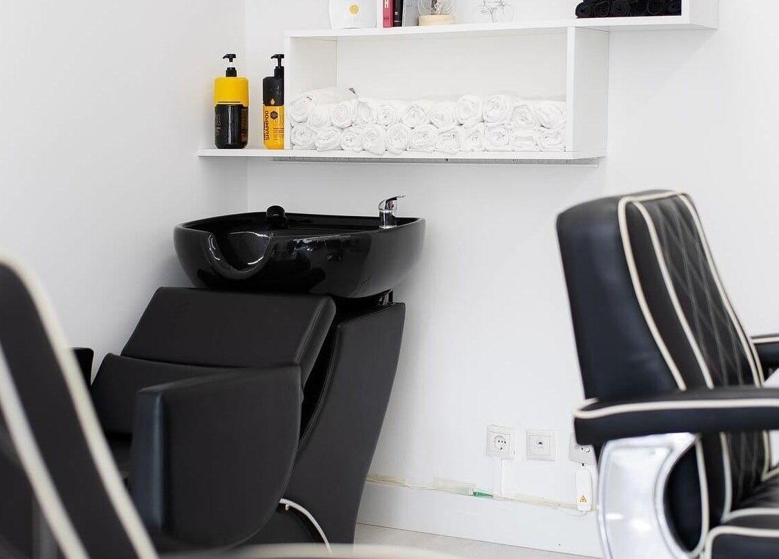 Cadeiras de barbearia elegantes na Boldmen’s Salon, Estoril, Lisboa, PT, com lavatório preto moderno.