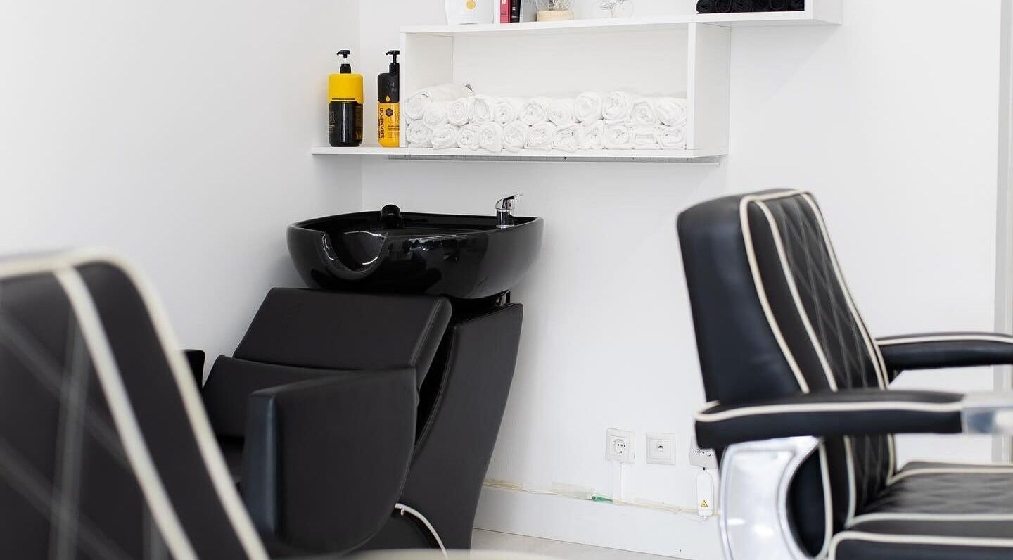 Cadeiras de barbearia elegantes na Boldmen’s Salon, Estoril, Lisboa, PT, com lavatório preto moderno.