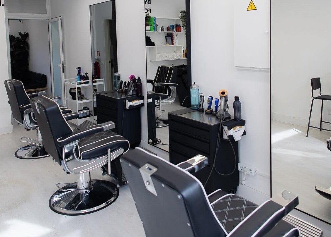 Interior moderno do Boldmen’s Salon em Estoril, Lisboa, PT, destacando cadeiras e espelhos elegantes.