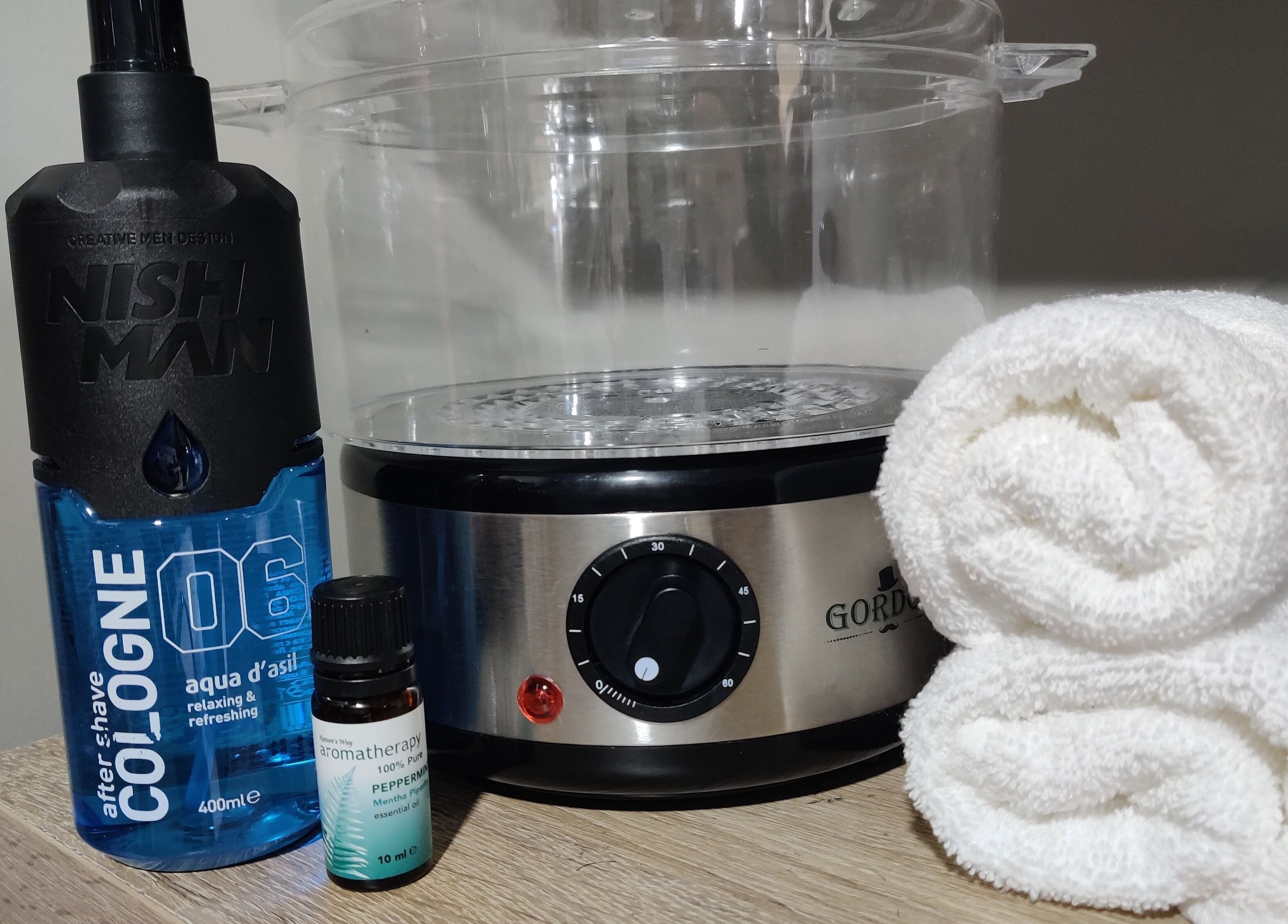 Barber Tina at JJ's Barber Shop grooming tools in Naxxar, MT, featuring cologne, oils, and towels.