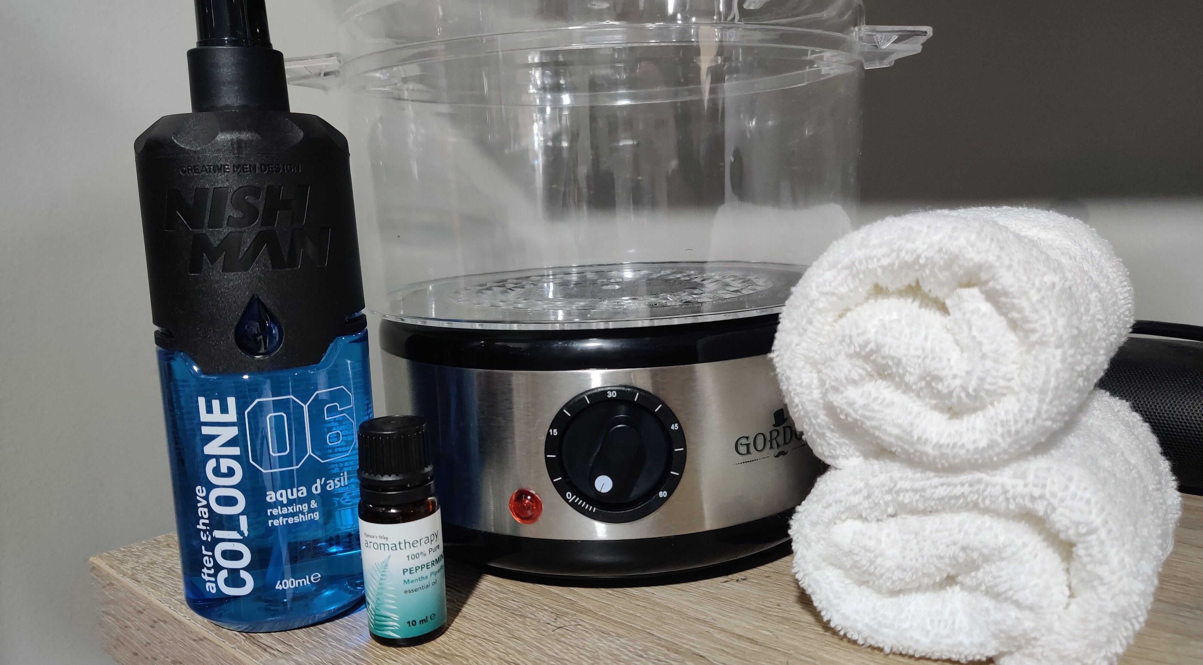 Barber Tina at JJ's Barber Shop grooming tools in Naxxar, MT, featuring cologne, oils, and towels.