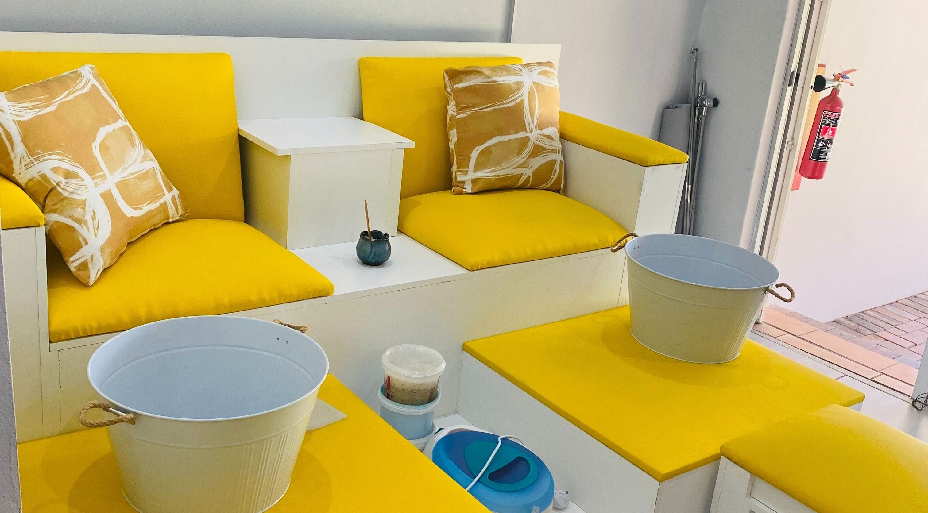 Bright seating area at Beauty by Yaya, Centurion, Gauteng, ZA, featuring yellow cushions and foot soak tubs.