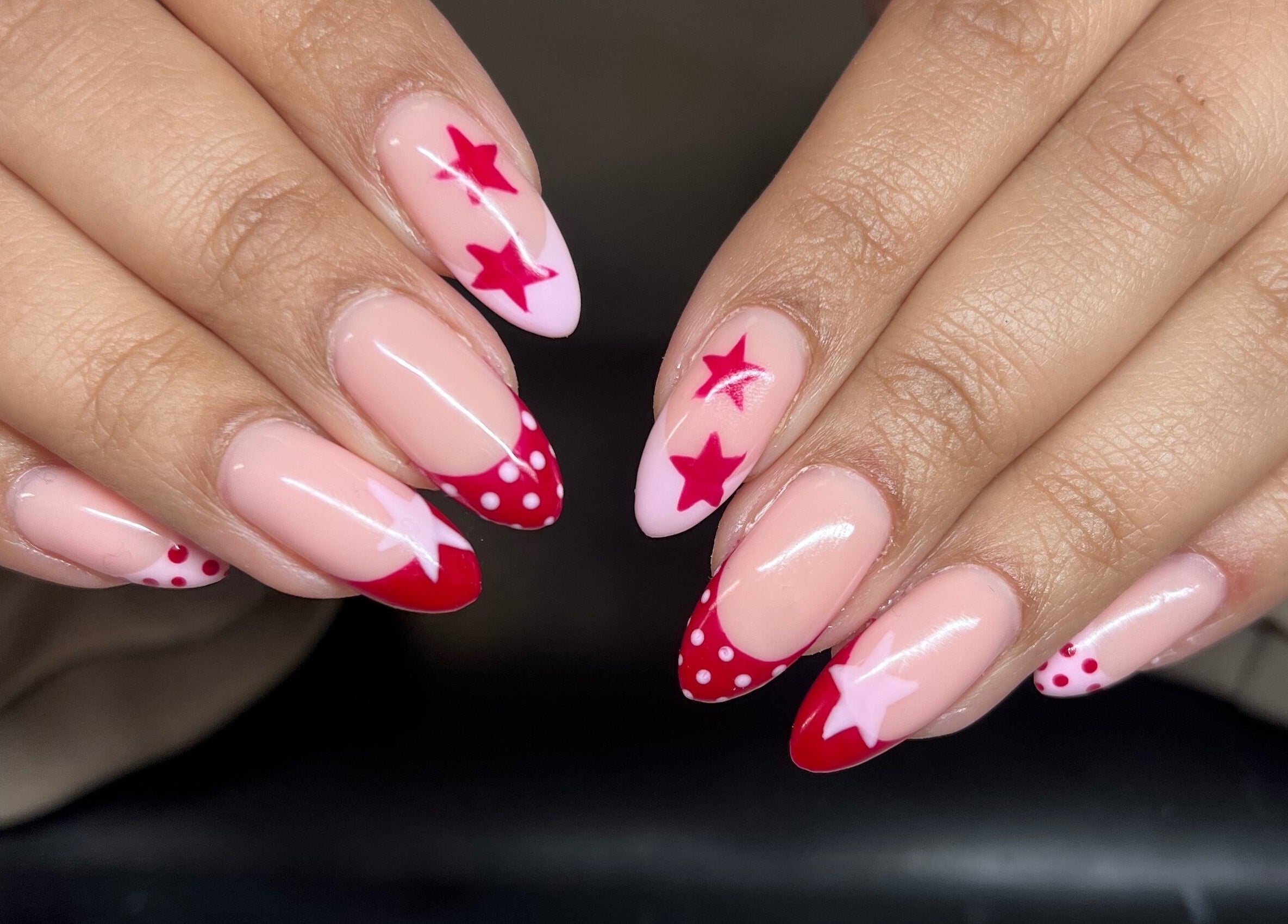 Chic star-themed nail art at Heathers Beauty in Harlow, England, GB, showcasing vibrant red and pink designs.