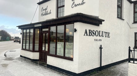 Exterior of Absolute Salon in Valley, Wales, GB on a snowy day, showcasing elegant signage.
