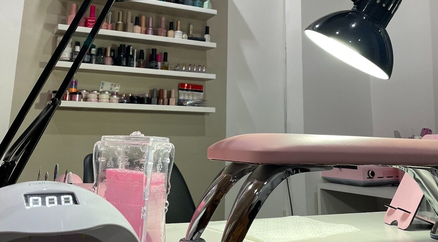 Estación de manicura en Lauris Fernández Studio, Mendoza, Mendoza, AR, con lámpara y esmaltes coloridos.