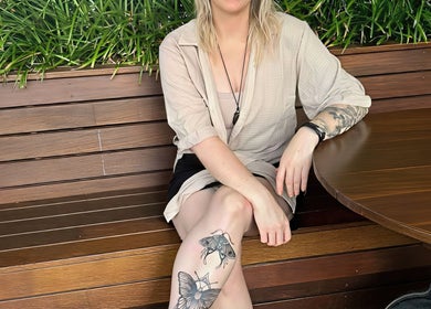 A serene woman seated at Cobi-Jane Intuitive Connections, Belmont North, New South Wales, AU with lush plants behind.