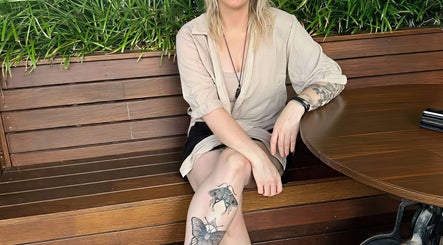 A serene woman seated at Cobi-Jane Intuitive Connections, Belmont North, New South Wales, AU with lush plants behind.