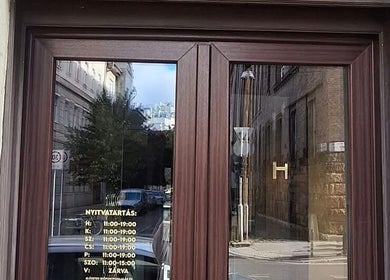 Elegant entrance of NailBerry in Budapest, Magyar, HU with clear glass doors and wooden frame.