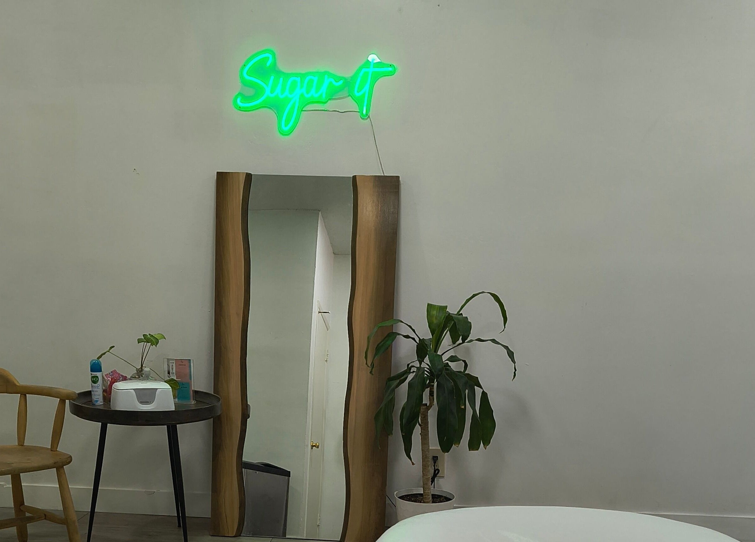 Calm interior at Sugar It Beauty, San Diego, California, US with mirror, chair, and plant.
