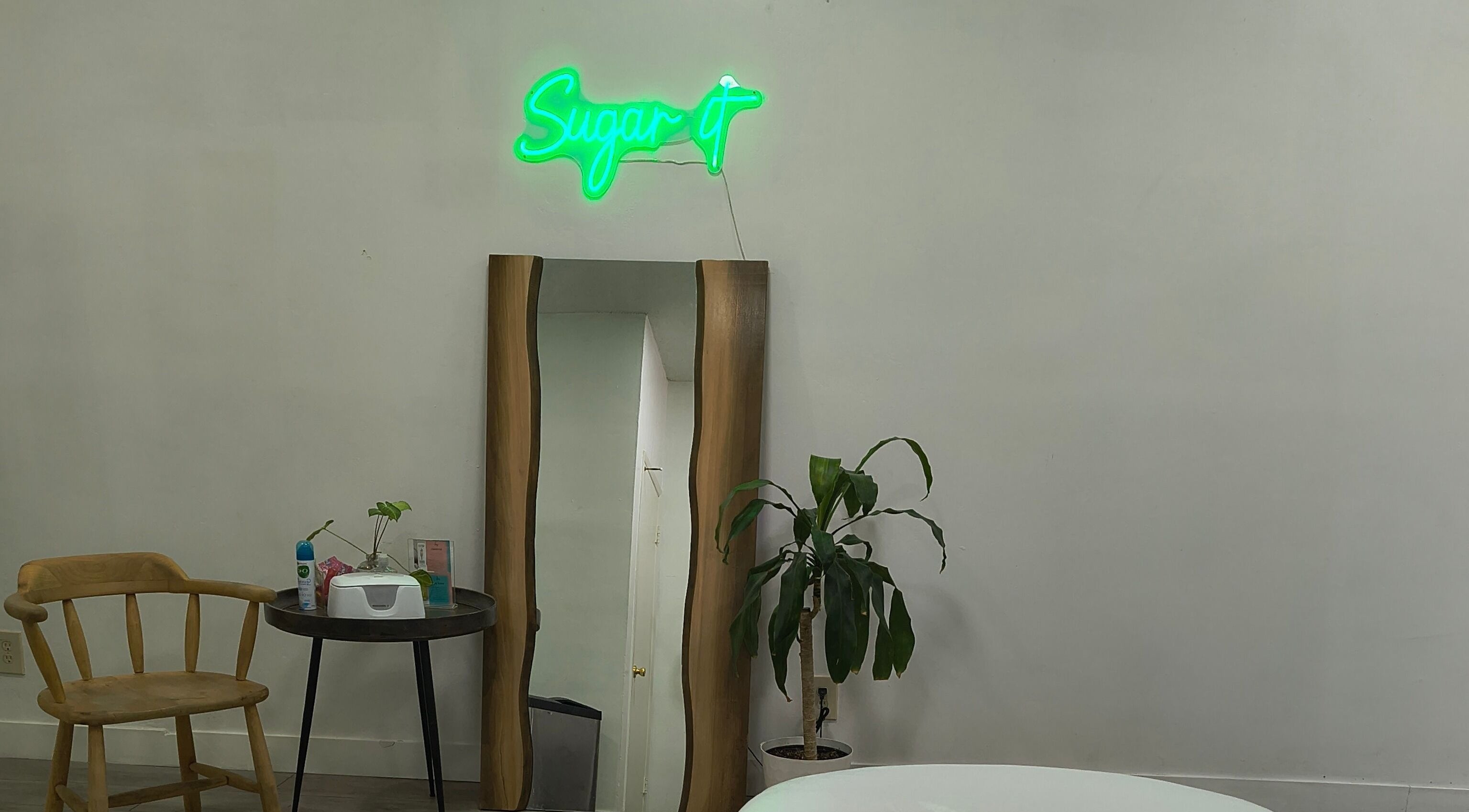 Calm interior at Sugar It Beauty, San Diego, California, US with mirror, chair, and plant.