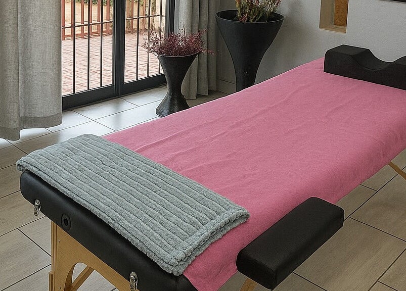 Massage table setup at Dramatyes Lash Lounge, Springs, Gauteng, ZA, with pink cover and soft cushions.