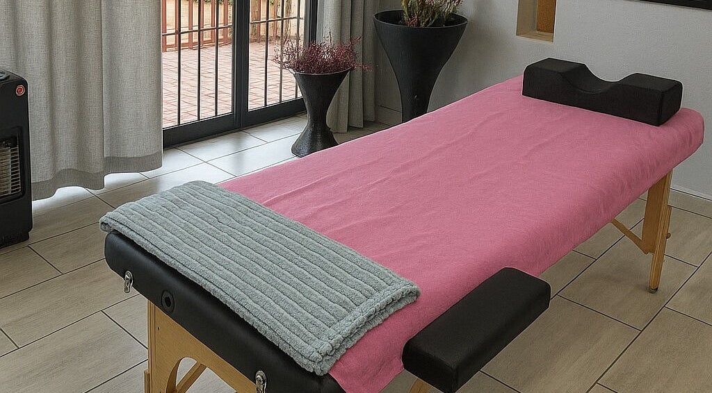 Massage table setup at Dramatyes Lash Lounge, Springs, Gauteng, ZA, with pink cover and soft cushions.