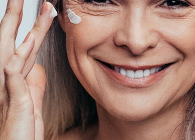 Smiling woman applying cream, showcasing skincare service at Nadine Louise, Salisbury, England, GB.