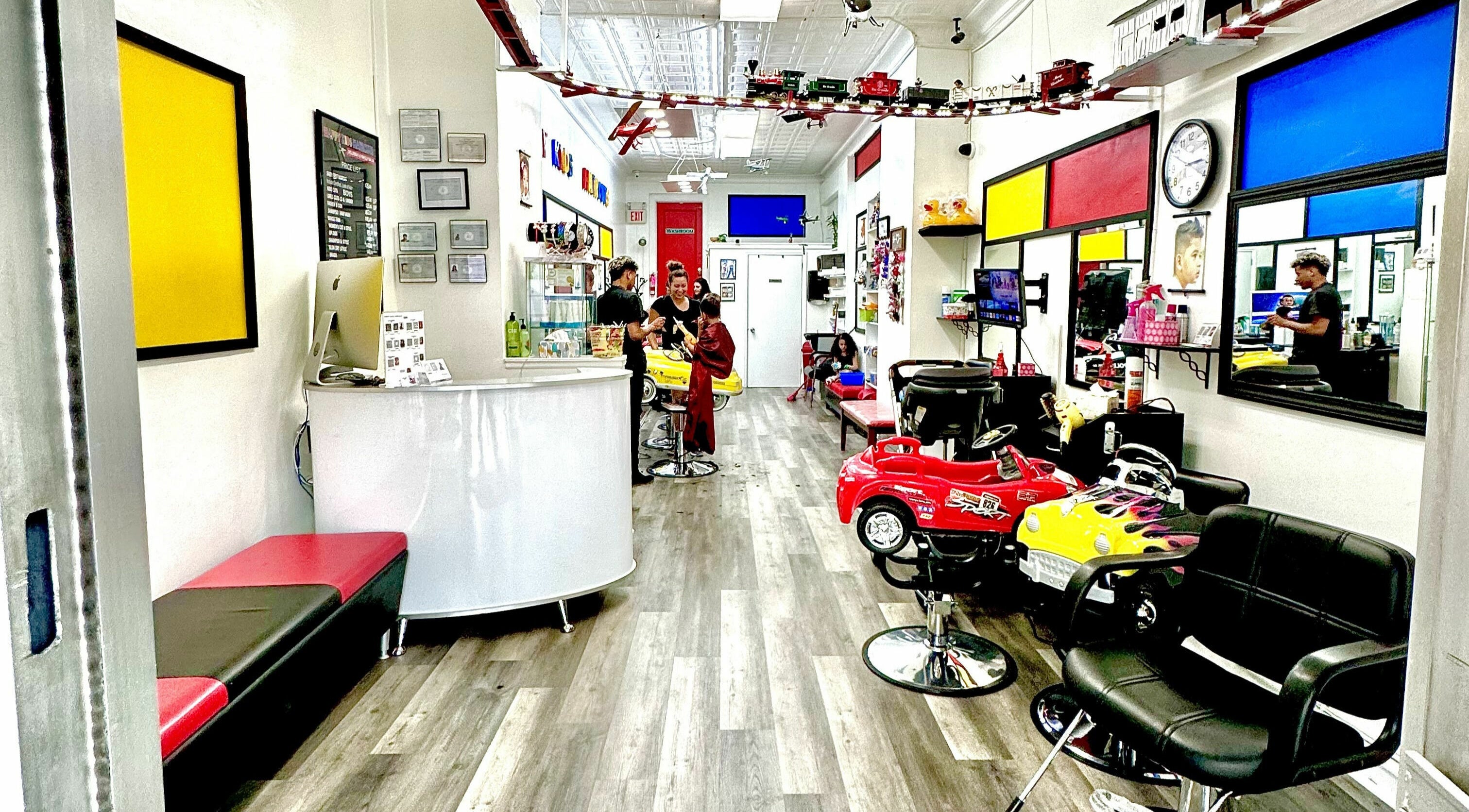 Bright interior of A and G Happy Kids Haircuts in Scarsdale, New York, US with colorful car-style chairs.