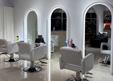 Interior moderno de BRACA Quito tennis, Quito, Pichincha, EC, con sillas blancas y espejos iluminados.