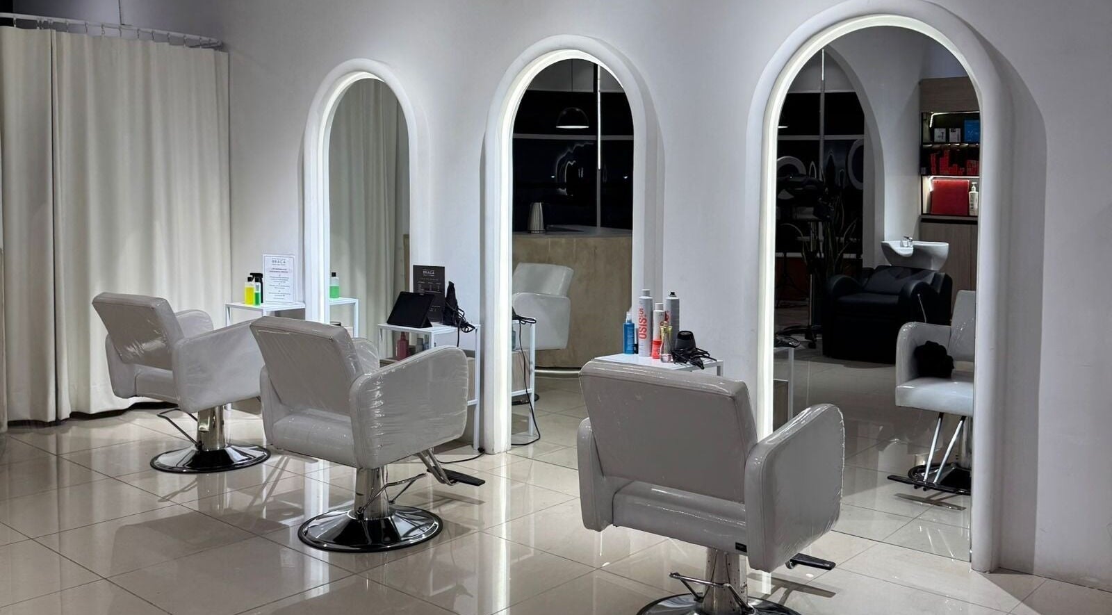 Interior moderno de BRACA Quito tennis, Quito, Pichincha, EC, con sillas blancas y espejos iluminados.